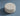 #Top view of C8 round pouf ottoman upholstered in cream bouclé fabric, featuring a soft-textured, cylindrical design on a light blue background.